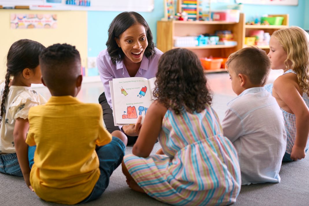 Children in a group reading a book together with a speech therapist