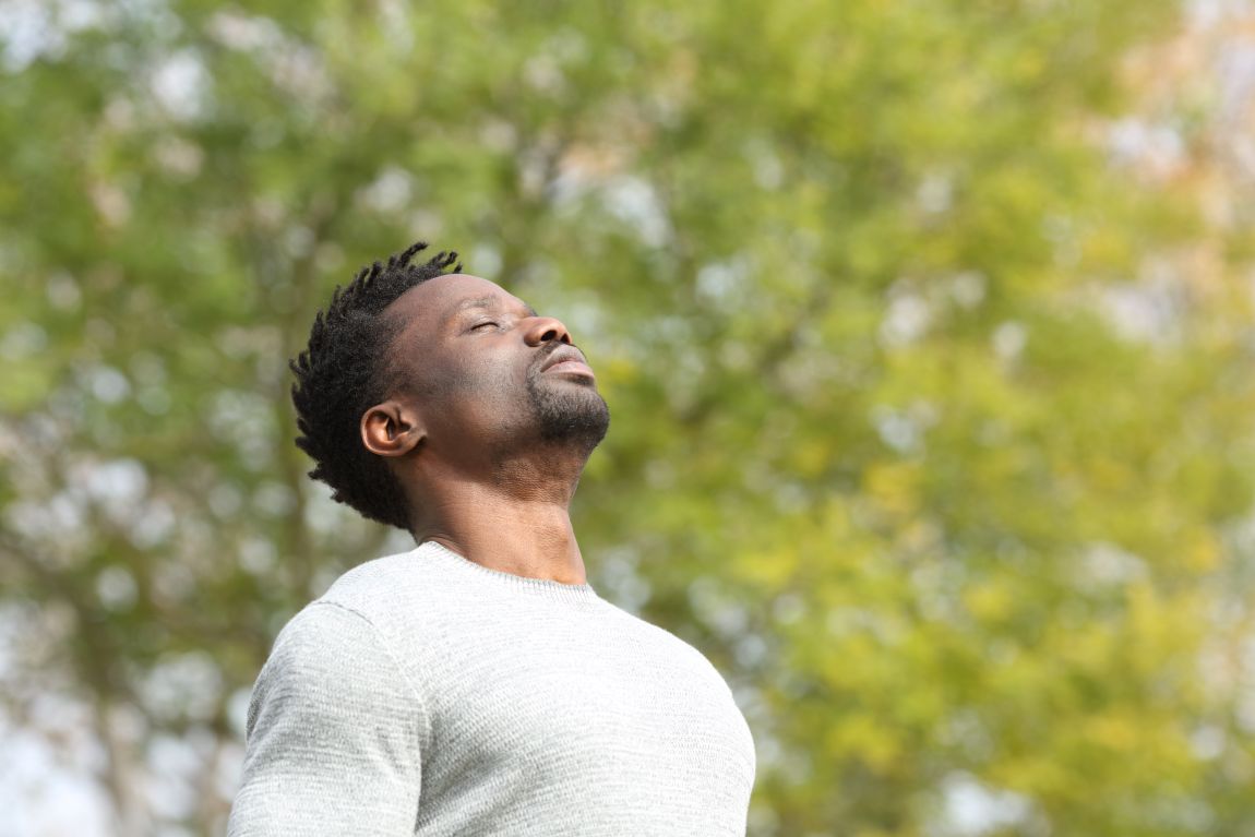 man breathing through nose in front of trees